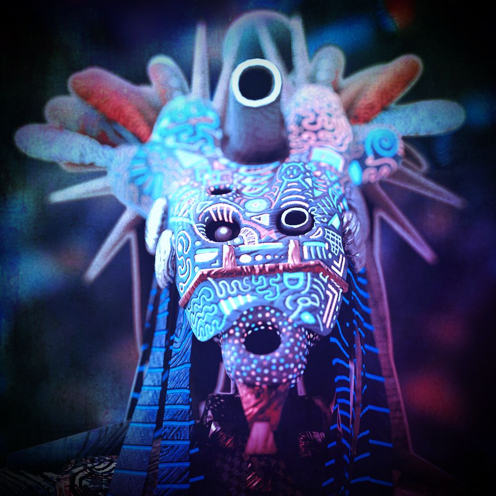 A spiky mask-like creature head covered in blue-and-white dotted patterns with red spines